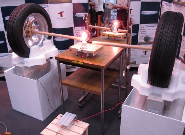 Опытная модель, представленная на выставке в Йокогаме. Энергия передаётся от металлических пластин через 10-сантиметровый слой бетона и автомобильные шины, питая лампу.