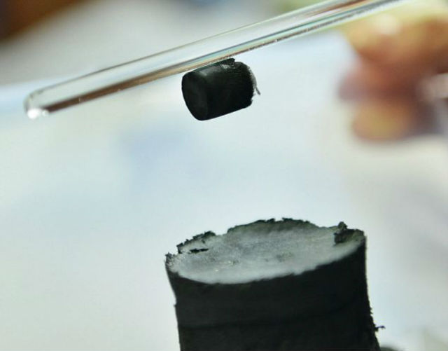 Исследователь демонстрирует, как кусочек нового материала держится на стеклянной палочке за счёт статического электричества (фото EPA).